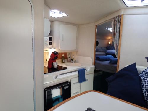uma pequena cozinha com um lavatório e um espelho em yacht vedette Arlequin em Gruissan