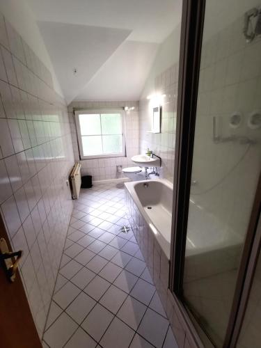 a white bathroom with a tub and a sink at Monteurzimmer am Bahnhof Biesenthal - 3 große Apartments in Biesenthal