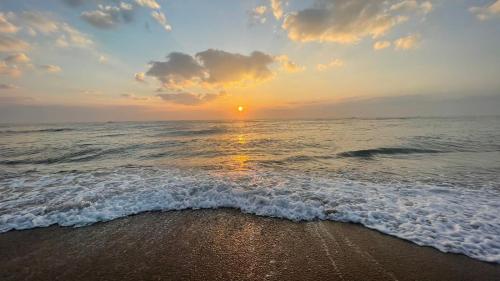 a sunset on a beach with the ocean at BareFootBay - Villa with Private Beach Access in Chennai