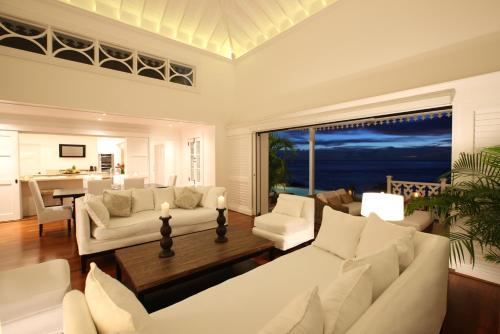 a living room with white furniture and a view of the ocean at Sugar Beach, A Viceroy Resort in Soufrière