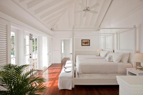 a white bedroom with two beds and a ceiling at Sugar Beach, A Viceroy Resort in Soufrière