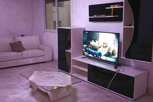 a living room with a tv and a couch at Tunis Comfort Family Home in Burj at Turkī
