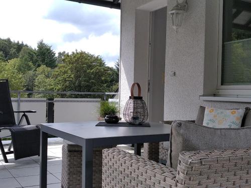 een patio met een tafel en stoelen op een balkon bij Ferienwohnung Zweite Heimat in Schmallenberg