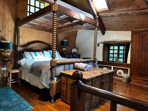 1 dormitorio con cama con dosel y suelo de madera en Coed Y Ddraig - themed 3 bedroom cottage, with bar & pool table, en Tregaron