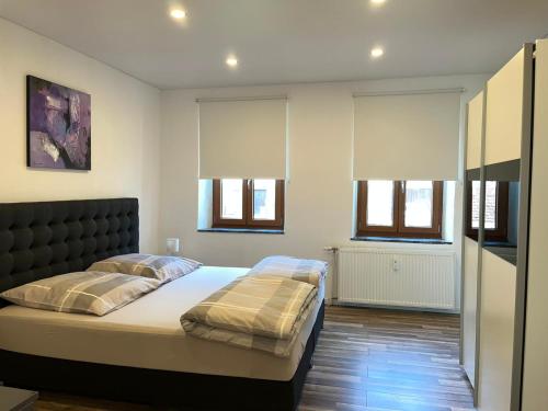 1 dormitorio con 1 cama grande y 2 ventanas en Ferienwohnung Göttert – Haus Erika, en Beckingen