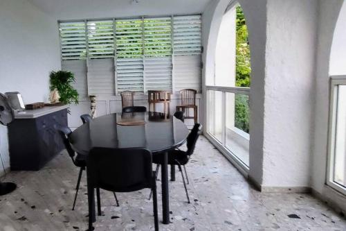 a dining room with a table and chairs and windows at Appartement magnifique vue mer in Le Gosier