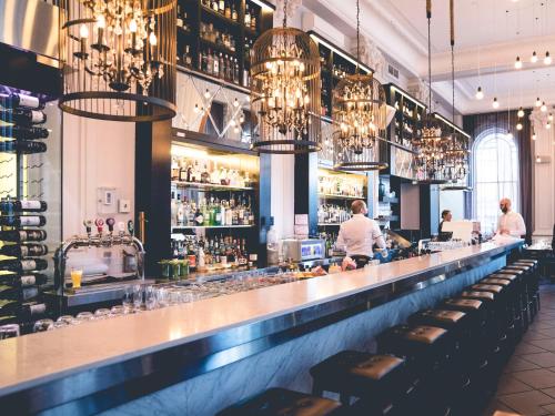 a bar in a restaurant with people standing at the counter at Hotel Place D'Armes in Montréal