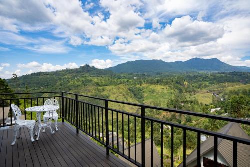 a balcony with two chairs and a table and mountains at Waterfall Villa by Opulence in Talawakele