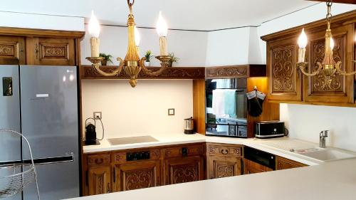a kitchen with wooden cabinets and a stainless steel refrigerator at Luxuriöse Villa Romantica in Gampel