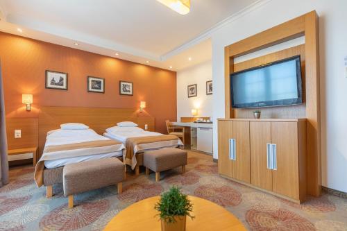 a hotel room with two beds and a flat screen tv at City Hotel Miskolc in Miskolc