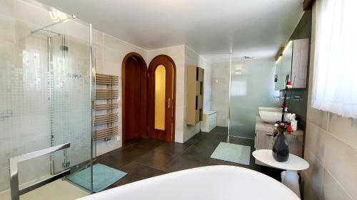a bathroom with a tub and a glass shower at Luxuriöse Villa Romantica in Gampel