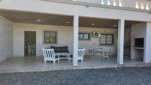 een veranda met witte stoelen en een tafel en stoelen bij DEPARTAMENTOS CIELO DE CAFAYATE in Cafayate