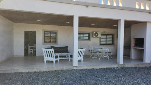 a porch with white chairs and a table and a table and chairs at DEPARTAMENTOS CIELO DE CAFAYATE in Cafayate