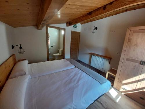 a bedroom with a large white bed with a wooden ceiling at IRATIKO KABIAK in Orbaiceta