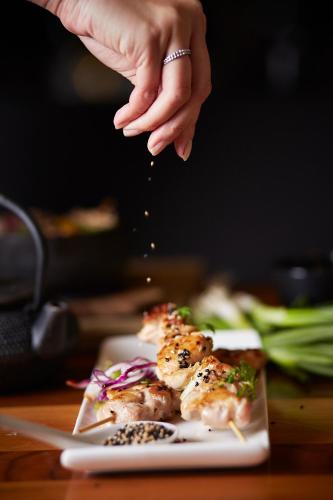 a person is sprinkling food on a plate of food at Hotel Place D'Armes in Montréal