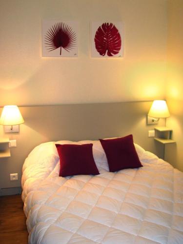 a bedroom with a white bed with two red pillows at VVF Bourgogne Auxois Morvan in Semur-en-Auxois
