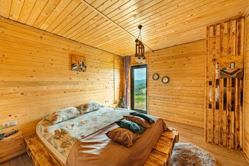 a bed in a wooden room with a window at Sweet Escape Vlădeasa in Rogojel