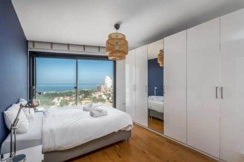 a bedroom with a bed and a large window at Moderne 3BR - Vue mer in Tel Aviv