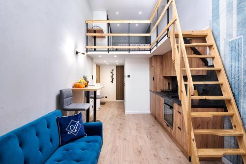ein Wohnzimmer mit einem blauen Sofa und einer Treppe in der Unterkunft Studio z widokiem na Piotrkowską Parking in Łódź