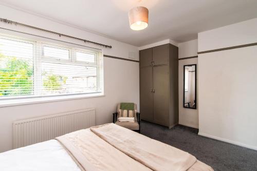 um quarto com uma cama, uma janela e uma cadeira em Immaculate home close to City Centre with large drive em Derby