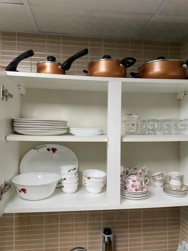 a kitchen shelf filled with dishes and pots and pans at One bedroom new brand in ajman in Ajman 