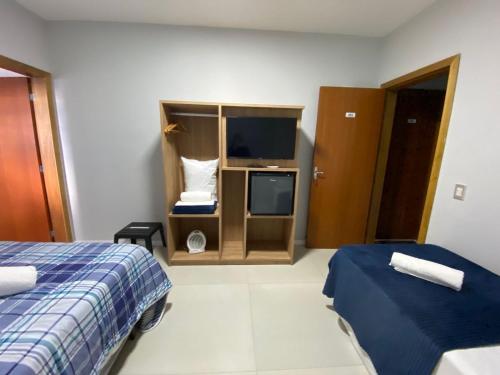 a hotel room with two beds and a tv at Pousada Ametista - Penha, SC - 1,5 km do Parque Beto Carrero World in Penha