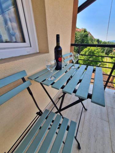 a blue picnic table with a bottle of wine and two glasses at Apartman Berlin Sokobanja in Soko Banja