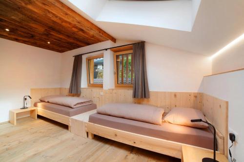 two beds in a room with wooden floors and windows at Herrischner Apartement 2 in Corvara in Passiria