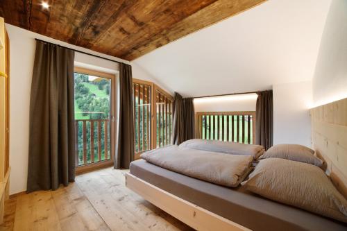 a bedroom with a bed and large windows at Herrischner Apartement 1 in Corvara in Passiria