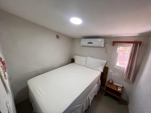 a small bedroom with a white bed and a window at Beira-mar Chácara Curimãs - Barroquinha, Ceará in Barroquinha