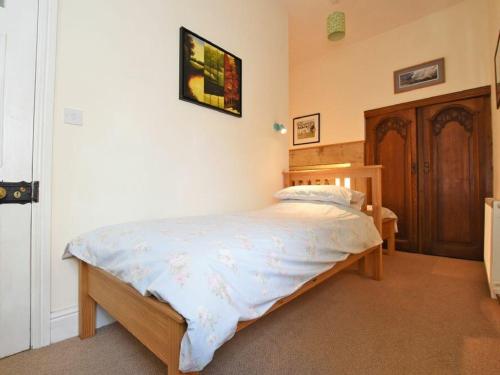 a small bedroom with a bed with a wooden frame at Riverbank Cottage in Alnwick