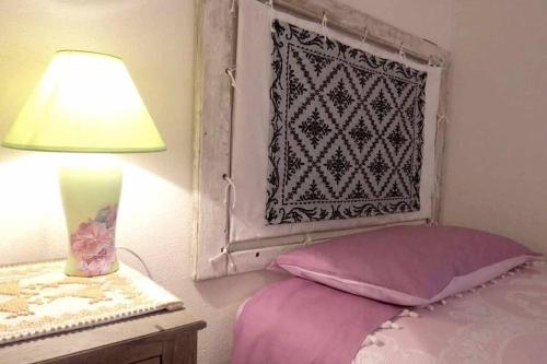 a bedroom with a bed and a lamp and a window at Taddore Green Lodge in Galtellì