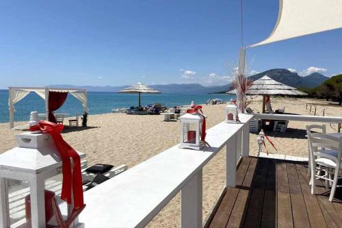 a beach with chairs and umbrellas on the sand at Taddore Green Lodge in Galtellì