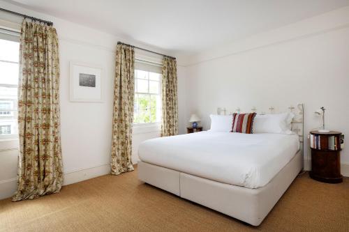 a white bedroom with a large bed and a window at Veeve - Eclectic Embrace in London