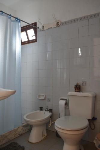 a white bathroom with a toilet and a sink at Brisas del Diablo 3 in Punta Del Diablo