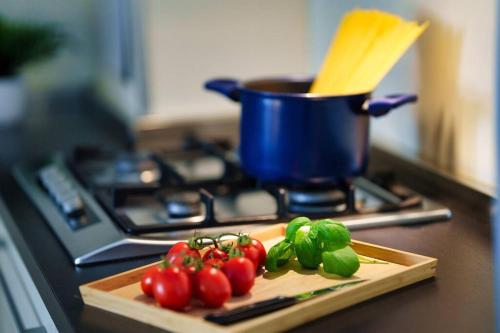 uma tábua de cortar com tomates e uma panela no fogão em [DUOMO-Cadorna] Cozy with WiFi & A/C em Milão