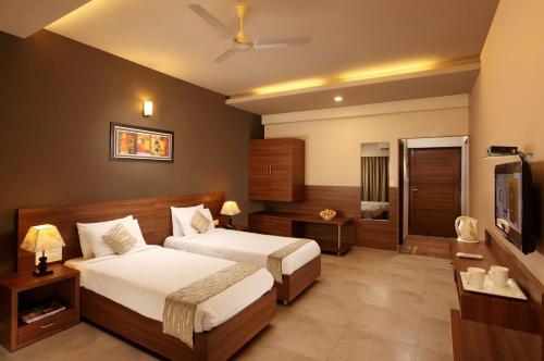 a hotel room with two beds and a television at Athome Comforts Panjim Donapaula in Panaji