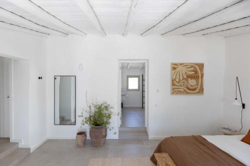 Habitación blanca con cama y espejo en Âmago Guesthouse en Santa Bárbara de Nexe