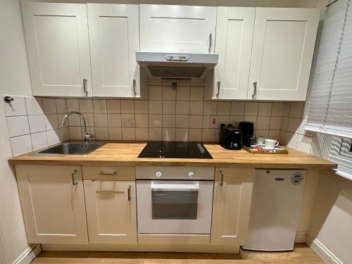 a kitchen with white cabinets and a sink at Premium Studio Flat 05 Near Tower Bridge in London
