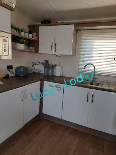 a kitchen with white cabinets and a sink at Lucy's Lodge in Rhyl