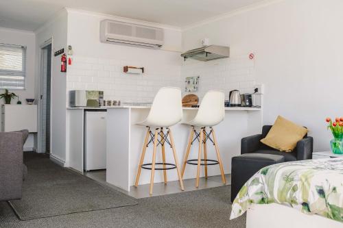 a room with a kitchen and two white stools at Brookwood Cottage in Somerset West