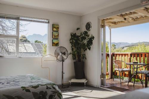 a bedroom with a bed and a balcony with a table at Brookwood Cottage in Somerset West