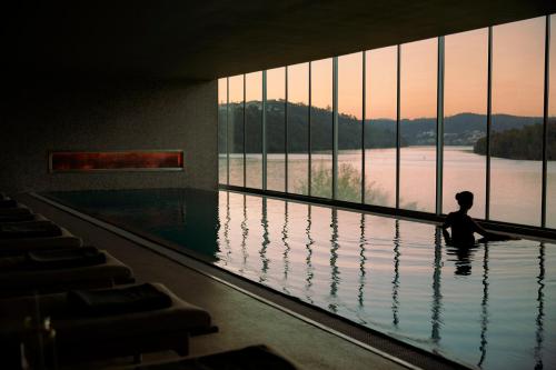 a person standing in a swimming pool looking out of a large window at Octant Douro in Castelo de Paiva