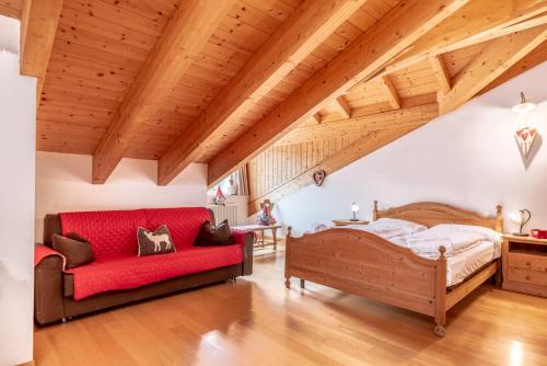 a bedroom with a red bed and a red couch at Residence Stella in Folgaria