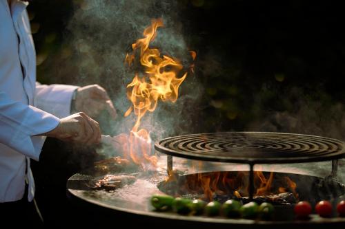 a man cooking food on a grill with fire at Octant Douro in Castelo de Paiva