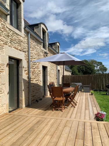 a wooden deck with a table and an umbrella at Les écuries du Nevez in Plonéour-Lanvern