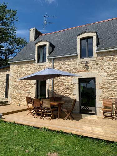 a wooden deck with a table and chairs and an umbrella at Les écuries du Nevez in Plonéour-Lanvern