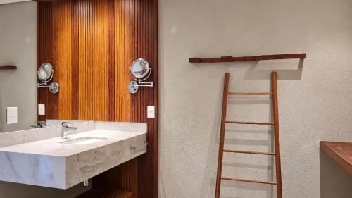 La salle de bains est pourvue d'un lavabo et d'une échelle à côté d'un miroir. dans l'établissement Qavi - Suíte luxuosa na rua principal #ÎledePipa, à Pipa