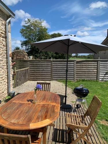 a wooden table with an umbrella on a patio at Les écuries du Nevez in Plonéour-Lanvern