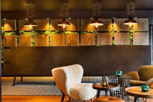 a lobby with chairs and tables and a wall with plants at Motel One Edinburgh-Royal in Edinburgh